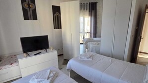 Una habitación de hotel con dos camas, un televisor, un escritorio y un armario.