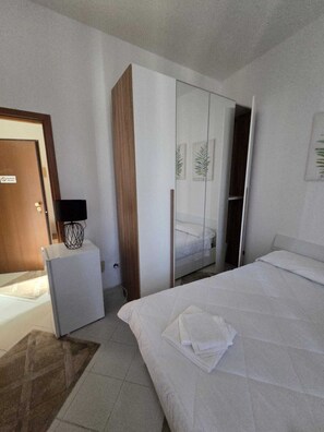 A bedroom with a bed, a wardrobe, a desk, and a door.