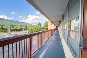 A balcony with a view of a parking lot and a mountain.