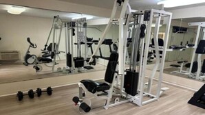 Uma academia com equipamentos de ginástica, espelhos e piso de madeira.