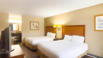 Une chambre d’hôtel avec deux lits, une télévision, un bureau et une lampe.