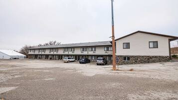 A motel with a row of rooms, a parking lot, and a tall utility pole.