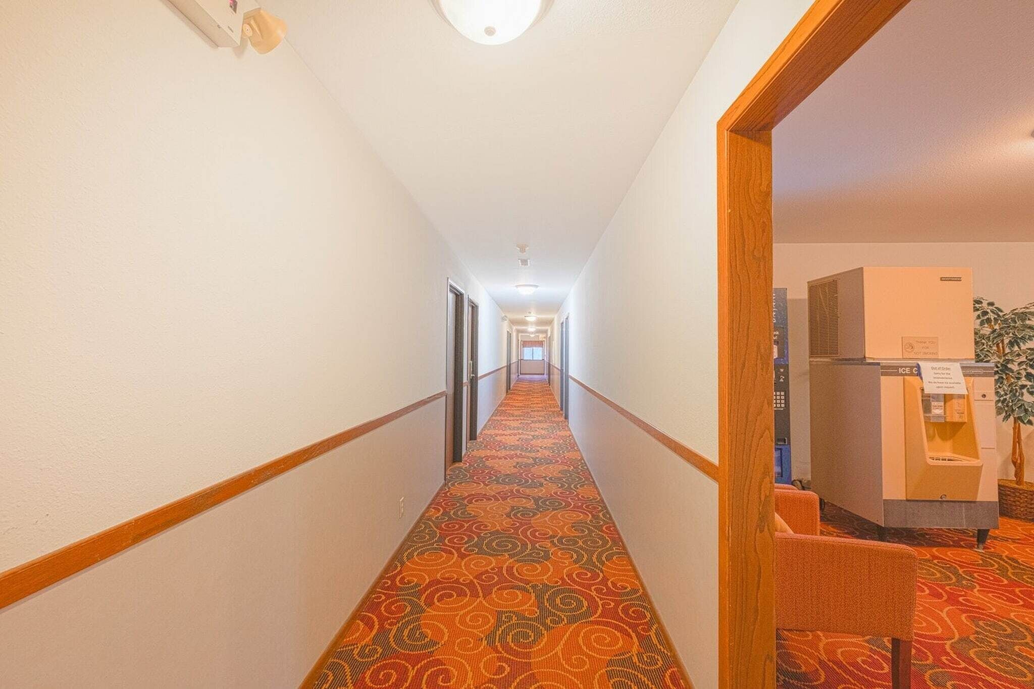 A hotel hallway with a patterned carpet, wooden handrails, and a vending machine.