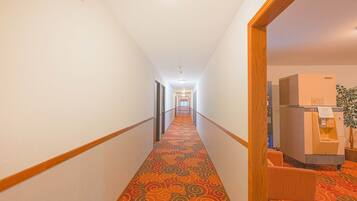 A hotel hallway with a patterned carpet, wooden handrails, and a vending machine.