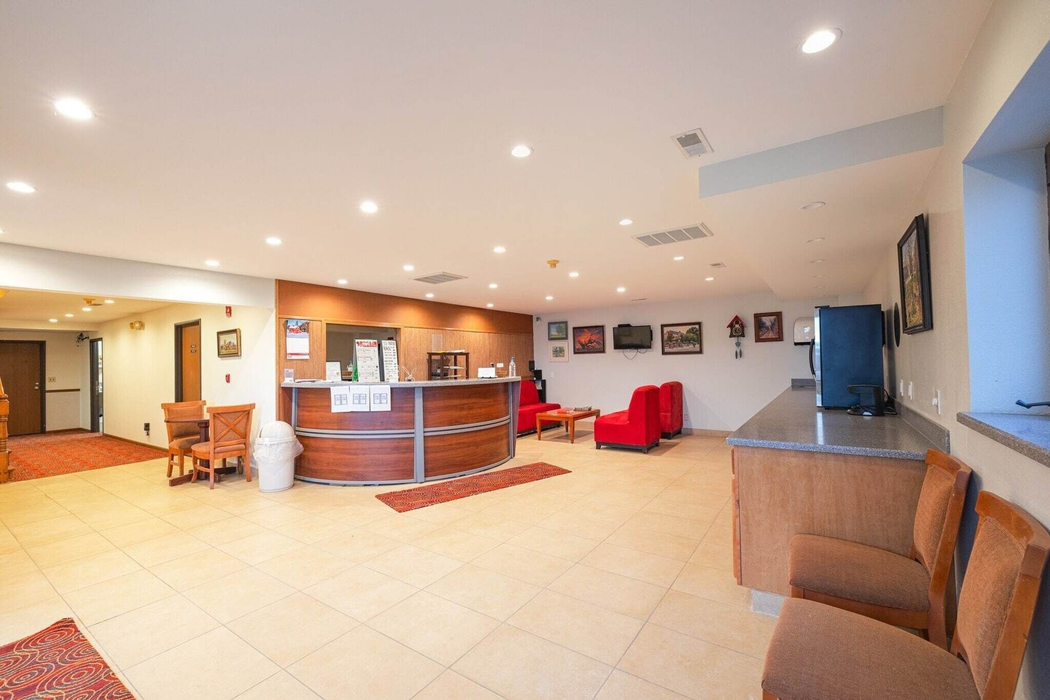 A hotel lobby with a reception desk, seating area, and a television.