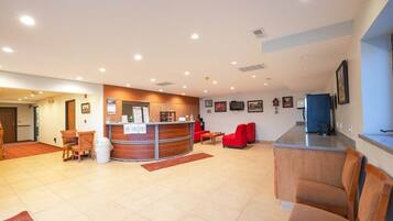 A hotel lobby with a reception desk, seating area, and a television.