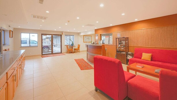 Um saguão de hotel moderno com área de cozinha, um sofá vermelho e um balcão de recepção.