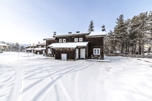 En träbyggnad med ett snötäckt tak, en liten veranda och en dörr.