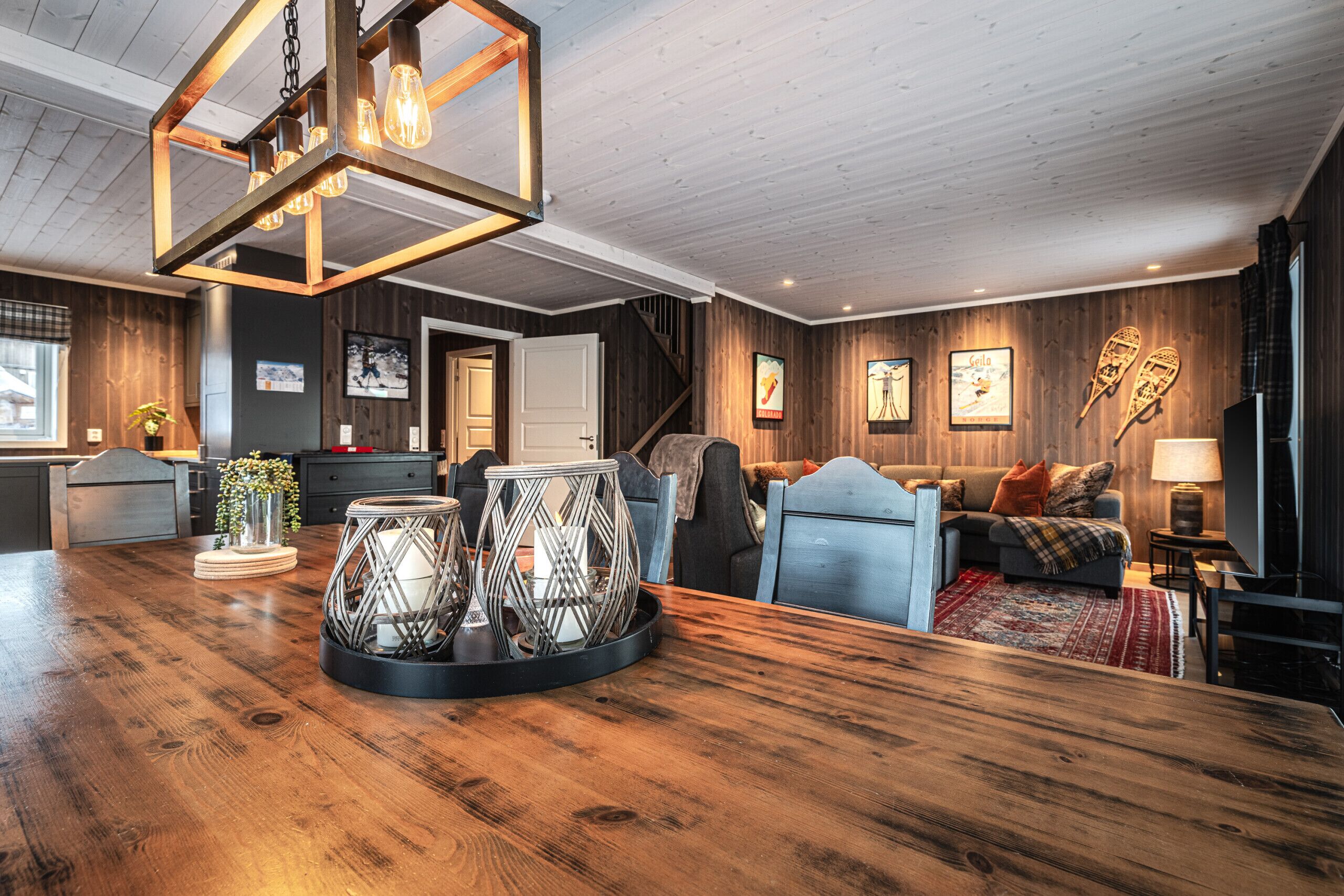 A wooden-finished room with a dining table, chairs, a sofa, and a TV.