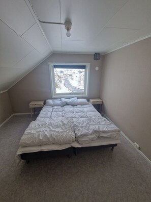 A bedroom with a bed, a window, a ceiling fan, and a nightstand.