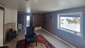 Una habitación con un ventanal grande, una silla azul, una alfombra y una chimenea.