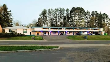 A motel with a central parking area, multiple rooms, and a covered walkway.
