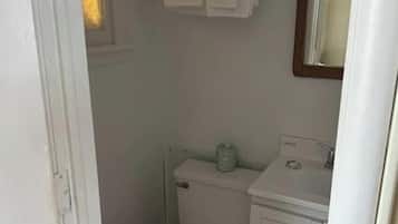 A small bathroom with a toilet, a sink, and a mirror. There is a towel rack above the sink with two towels hanging.