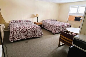 Ein Zimmer mit zwei Betten, einem Tisch, einem Stuhl und einer Mikrowelle.