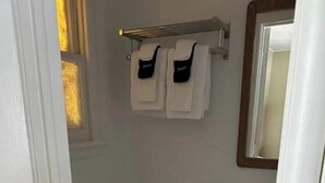 Ett litet badrum med en toalett, ett handfat och en spegel. Ovanför handfatet finns en handduksställare med två handdukar hängande på den.