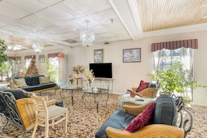 A spacious living room with a large flat-screen TV, comfortable seating, and a Christmas tree.