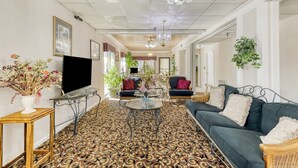 A living room with a patterned carpet, a television, and various seating arrangements.
