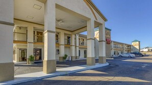 A hotel with a covered outdoor area, multiple balconies, and a parking lot.