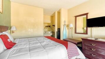 A hotel room with a bed, a dresser, a mirror, and a television.