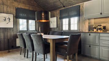 Un comedor con una mesa de madera, sillas tapizadas grises y una lámpara colgante.