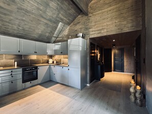 A modern kitchen with grey cabinets, a built-in oven, and a wooden ceiling.