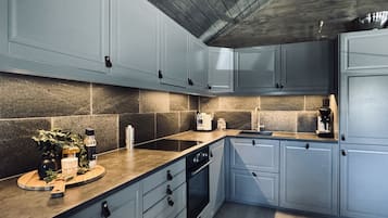 Une cuisine moderne avec des meubles gris, un pare-feu en pierre et un plan de travail en bois.