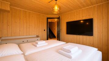 A wooden-paneled room with two beds, a TV, and a staircase.