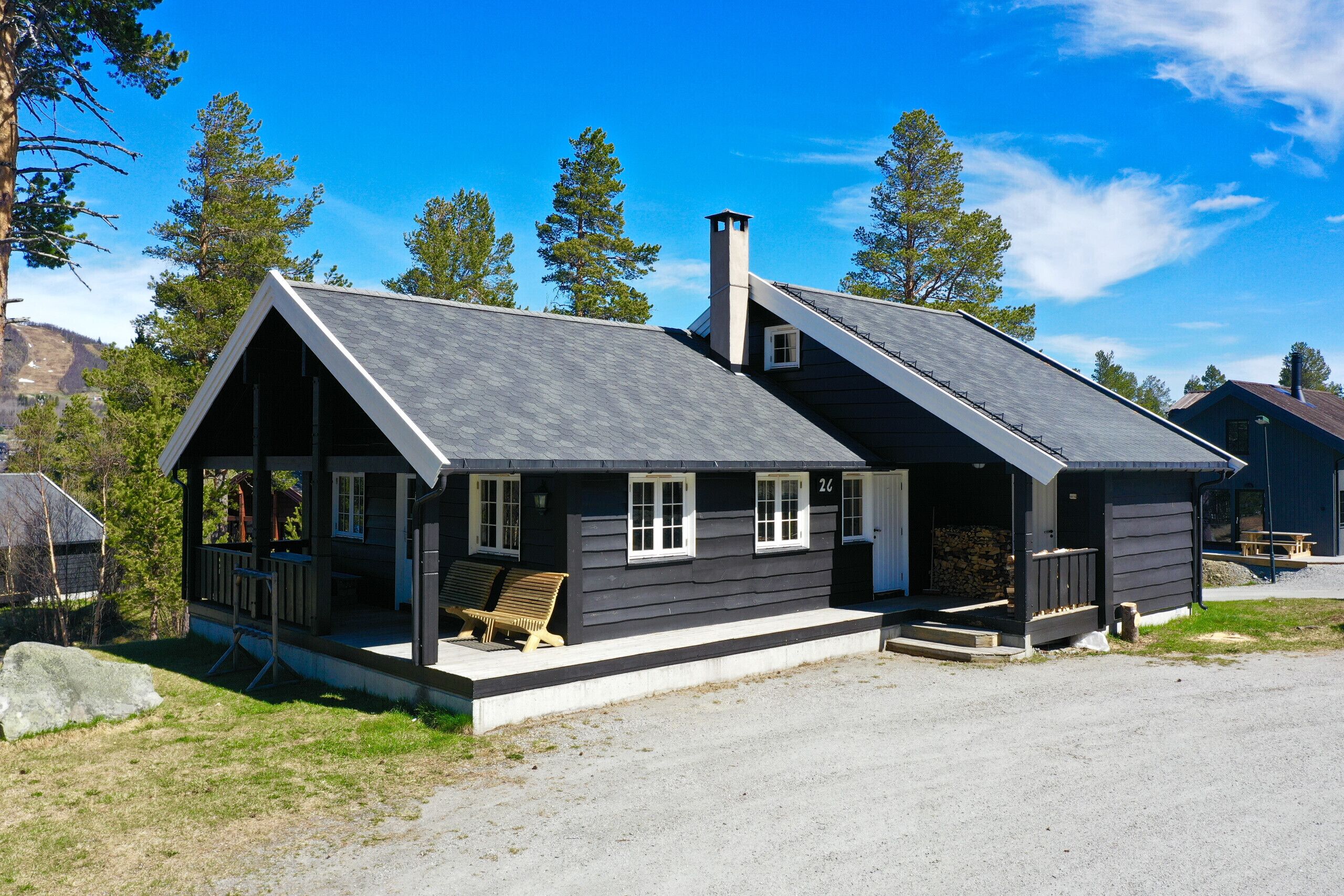 Une cabane à deux étages, dotée d’un porche, d’une cheminée et du numéro « 26 » peint sur le côté.