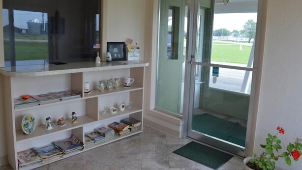 A reception area with a glass door, a reception desk, and a shelf with books and decorative items. - 2 Full Beds Non-Smoking (Wathena, KS)
