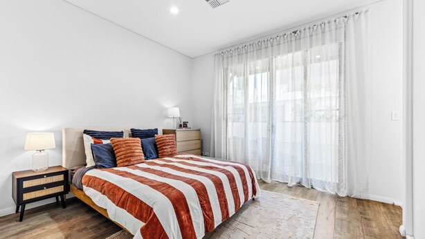 Un dormitorio con cama, mesitas de noche, cómoda y cortinas traslúcidas.