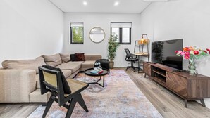 Una sala de estar moderna con un sofá, una mesa de centro, un televisor y un escritorio con una silla.