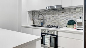 Cocina moderna con estufa a gas, pileta de acero inoxidable y salpicadero de azulejos.