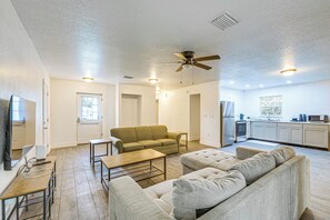 Ein Wohnzimmer mit Sofa, Couchtisch, Fernseher und Deckenventilator.