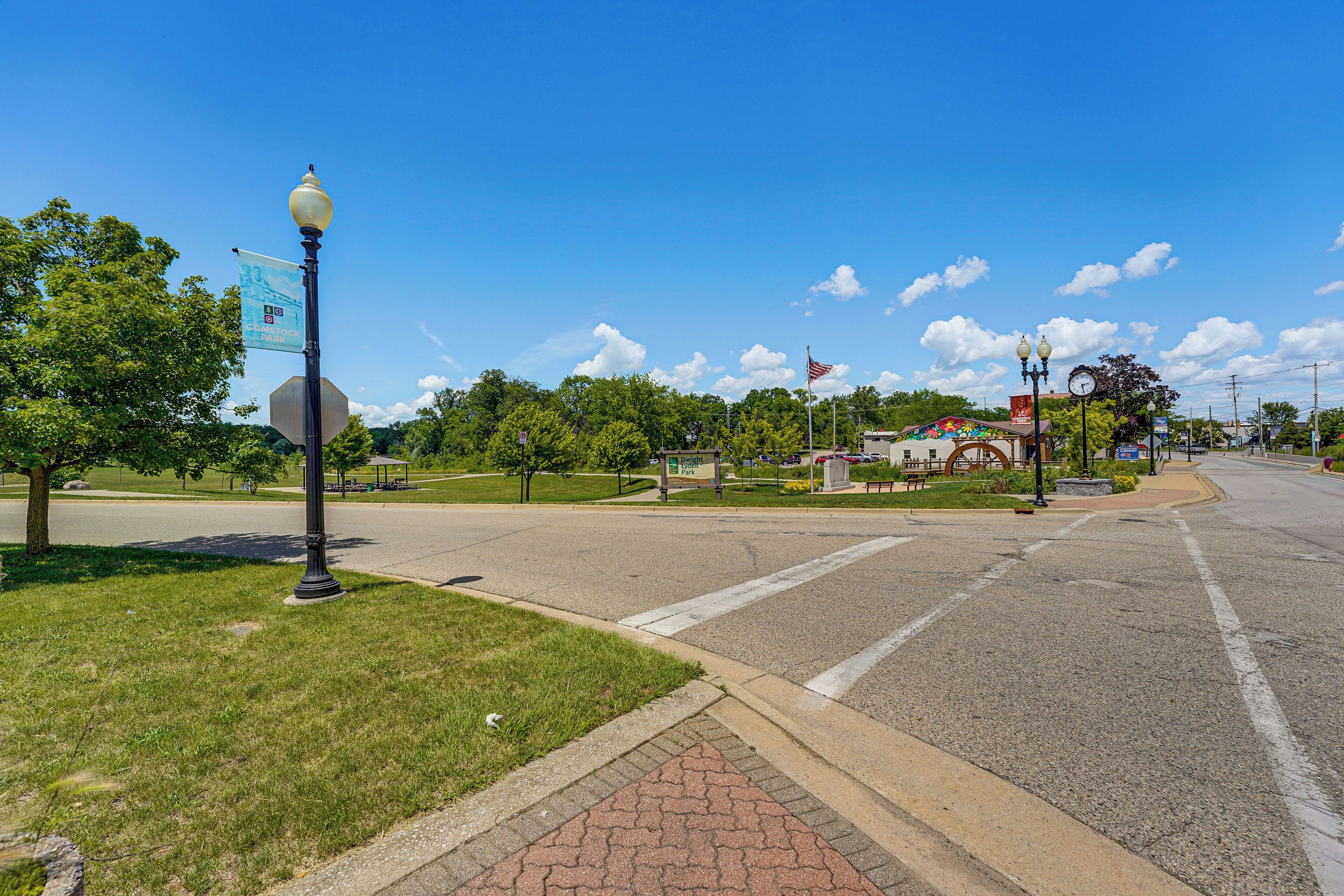 A paved intersection with a stop sign, a street lamp, and a flagpole with an American flag.