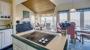 A kitchen with a central island, a dining area with chairs, and a view through large windows. - Direct Beach Access! Quiet Diamond Point Retreat (Sequim)