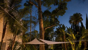 An outdoor seating area with a sofa and chairs, surrounded by trees and a clear night sky. - Magnífica Villa 5 dormitorios con piscina privada cerca Banus (Marbella)