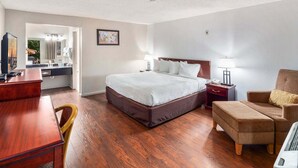 Une chambre d’hôtel avec un lit, un bureau, une chaise et une petite table.
