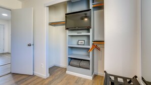 Ein begehbarer Kleiderschrank mit Regalen, einem Flachbildfernseher und einer Tür.
