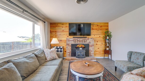 Ein Wohnzimmer mit einer Couch, einem Couchtisch, einem Kamin und einem an der Wand befestigten Fernseher.