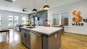 Een moderne keuken met een centraal eiland, hangende lampen en een groot raam.
