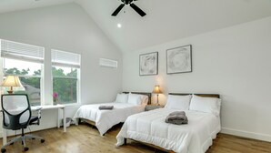 Een slaapkamer met twee bedden, een bureau, een stoel en een plafondventilator.