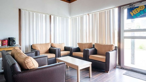 Ein Hotelzimmer mit Sitzgelegenheit, inklusive Sofas und einem Couchtisch, großen Fenstern mit Jalousien und einer Tür mit Hinweis auf HBO.