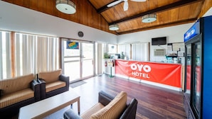 Eine Hotelhalle mit Holzbalkendecke, einer Rezeption und Sitzbereichen.