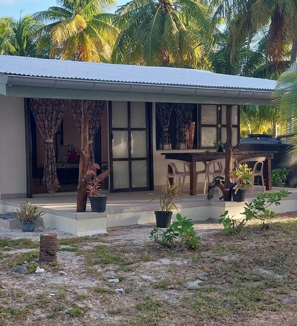 Una casa con porche cubierto, plantas en macetas y un pequeño espacio con mobiliario exterior.