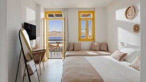 Un dormitorio con cama, escritorio, silla, televisor y vista al mar.