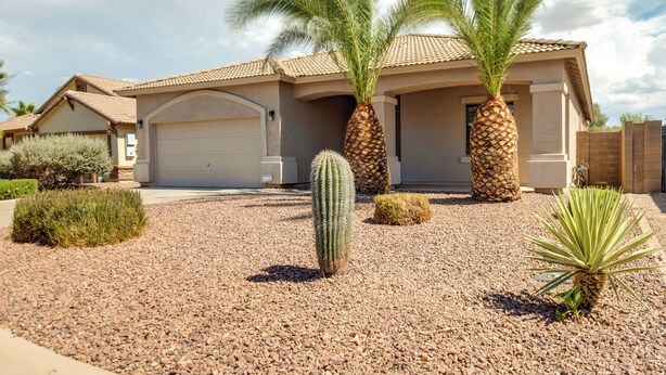 A residential house with a garage, palm trees, and a cactus in the driveway. - Golf, Gamble, Relax Poolside! Maricopa Desert Home (Maricopa)