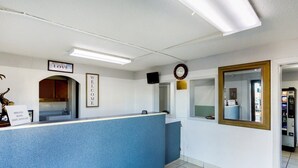 A reception area with a blue counter, a welcome sign, a clock, and a mirror. - Pensacola FL | 2 Full Bed (Pensacola FL)
