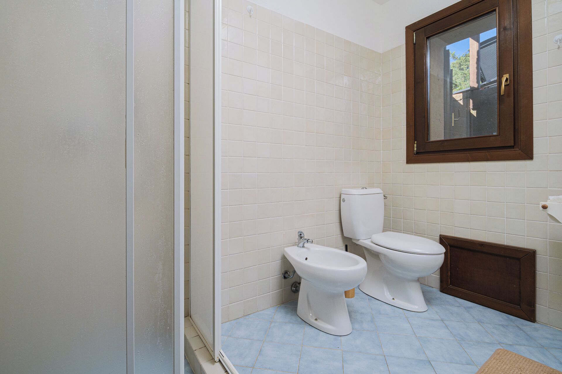 A bathroom with two toilets, a sink, and a window.