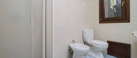 A bathroom with two toilets, a sink, and a window.