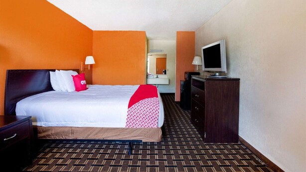 A hotel room with a bed, a TV, a dresser, and a mirror.